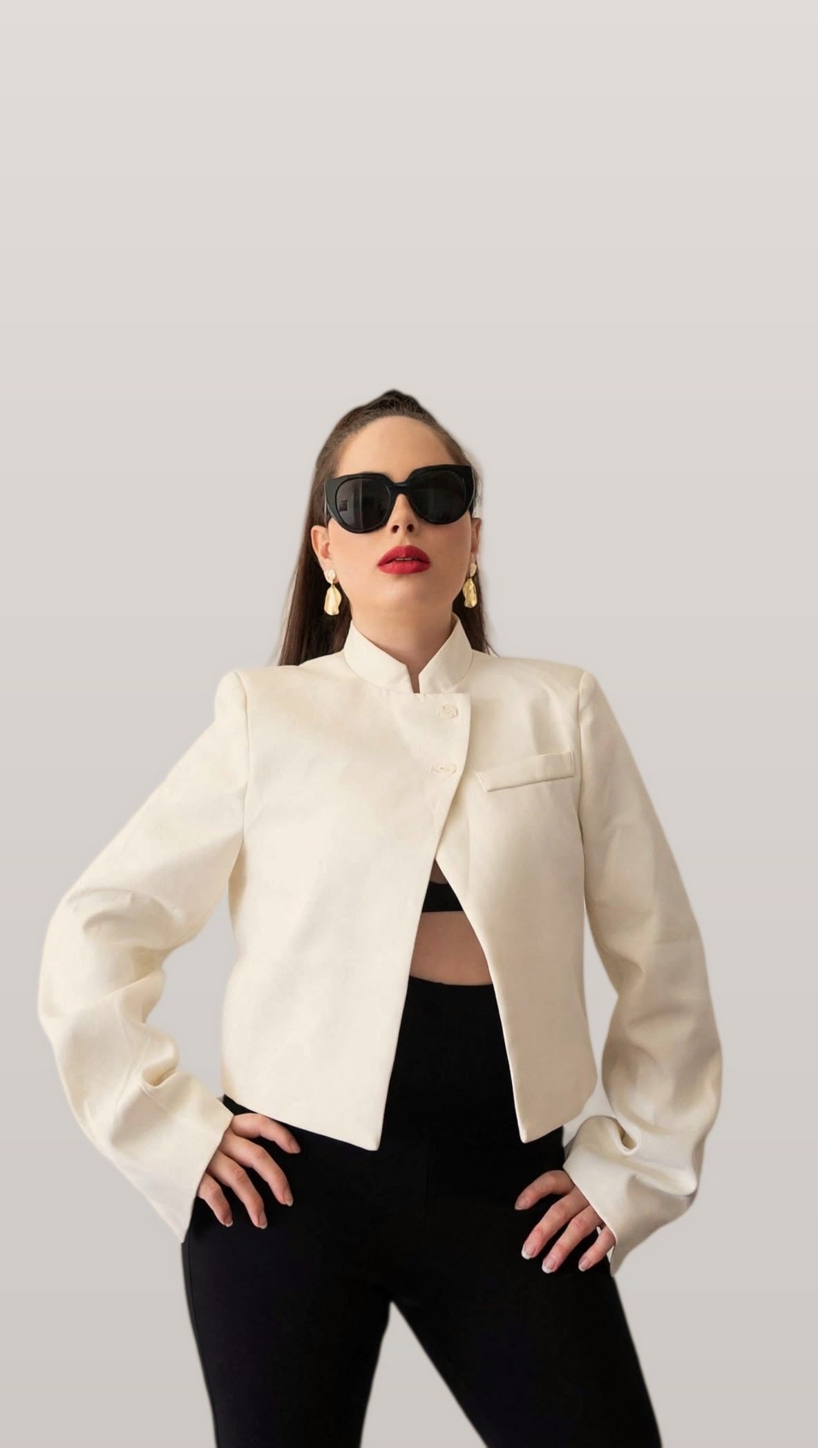Cream stand collar blazer worn open over black trousers, front view